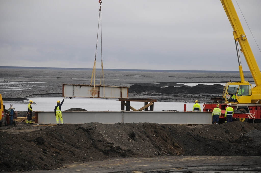 Stálbitar hífðir á réttan stað í bráðabirgðabrúnni yfir Múlakvísl.