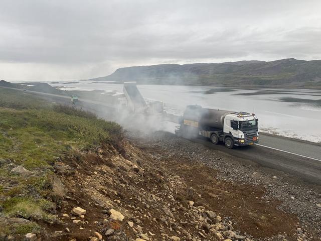 Vinna við lagningu klæðingar á veginum um Teigsskóg.