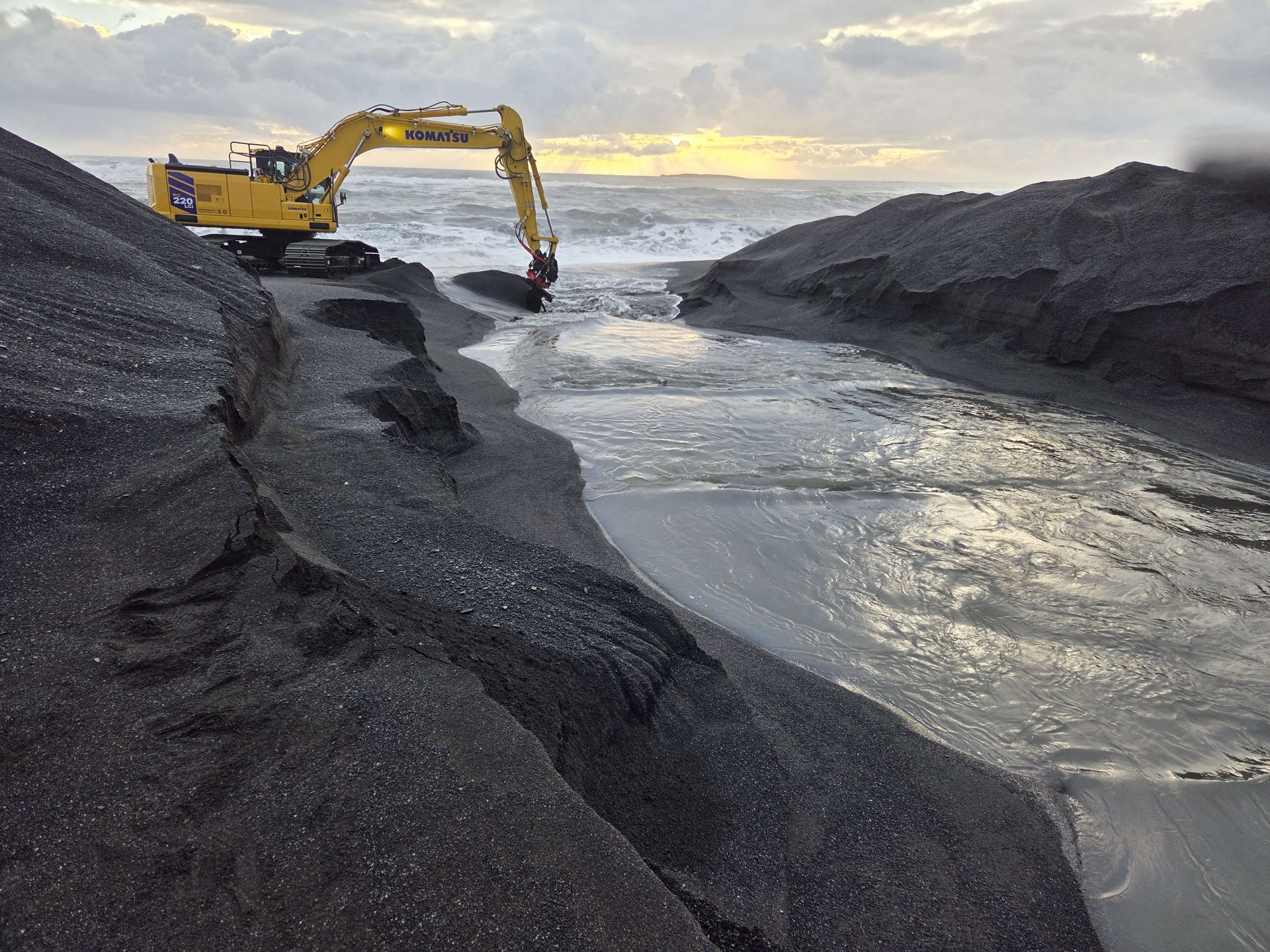 Verktakinn grefur rennu til að vatn flæði út úr Lónsfirði.